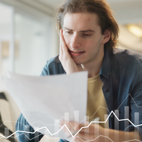 Rapaz sentado à secretária olha para uma folha com o conteúdo do curso investe.